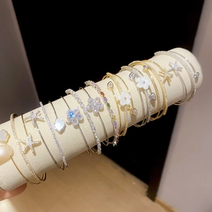 Elegant zircon and mother-of-pearl flower open bangles displayed on a velvet roller