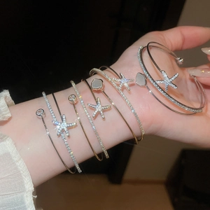 Detailed view of layered zircon starfish bangles and pearl flower open bracelets