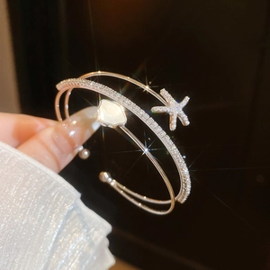 Close-up of elegant double-layer open bangle with zircon starfish and shell flower
