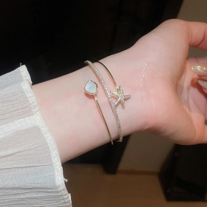 Close-up of elegant double-layer gold bangle with shell flower and zircon starfish charm