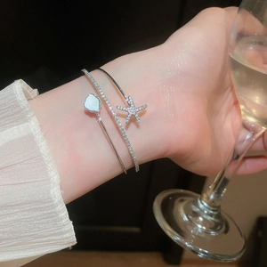 Close-up of elegant double-layer silver bangle with starfish and shell flower motifs