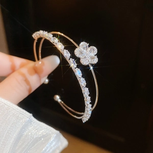 Detailed view of an elegant double-layered open bangle with a sparkling zircon flower