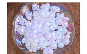 Close-up of iridescent white resin charms in heart, star and bear shapes for DIY crafts