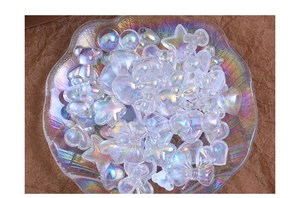 Macro view of aurora laser resin bear and star charms in a shell-shaped glass tray