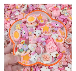 Detailed close-up of pink mixed cartoon resin charms and Hello Kitty cabochons for DIY crafts