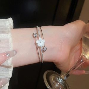 Close-up of a silver double-layer bangle featuring a white flower and cubic zirconia.