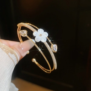 Detail of gold double-layered bangle with shell flower and sparkling zircons