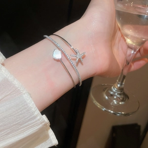 Close-up of elegant double-layered silver bangle with zircon starfish and shell flower