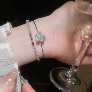 Elegant close-up of a silver zircon flower bangle and colorful crystal bracelet set.