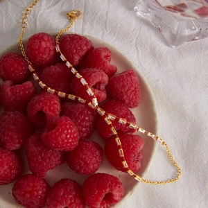 Détail d'un bracelet de doigt en acier doré avec zircons rectangulaires sur framboises.