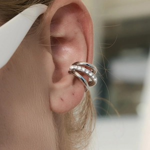 Detail of a silver triple-row stainless steel ear cuff with sparkling crystal stones