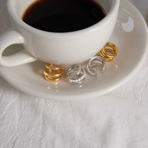 Detail of gold and silver multi-layer ear cuffs on a white coffee saucer