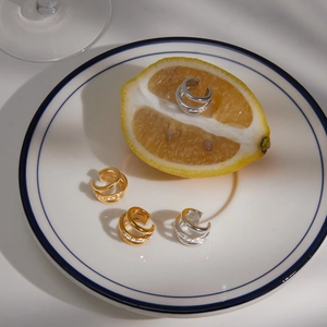 Close-up of gold and silver titanium steel ear cuffs with sparkling crystal inlays on a plate