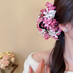 Vue détaillée d'une pince à cheveux à fleurs roses et blanches sur les cheveux du modèle