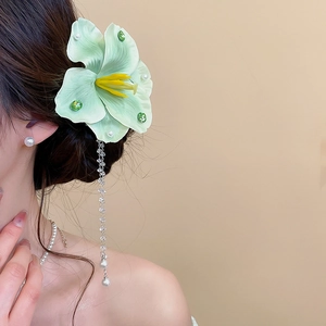 Detail einer hellgrünen Blumen-Haarspange mit schwingenden Perlenquasten an einem Model