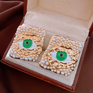 Detalle de pendientes vintage de perlas y esmalte verde de ojo turco en estuche de joyas