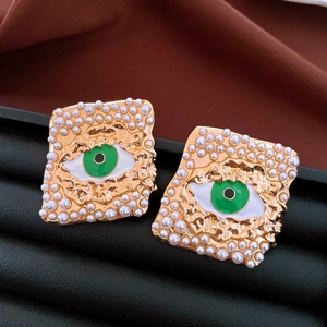Primer plano de pendientes cuadrados dorados con borde de perlas y diseño de ojo verde