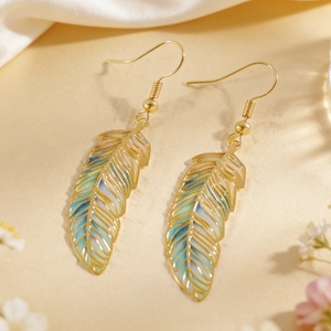 Macro view of vintage gold earrings featuring colorful feather-shaped enamel details