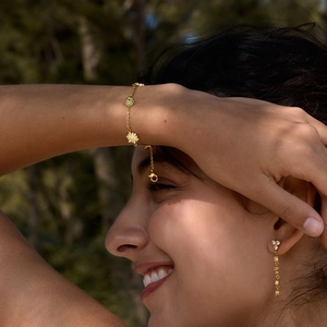 Detail view of a gold stainless steel bracelet with daisy charms and cubic zirconia stones.
