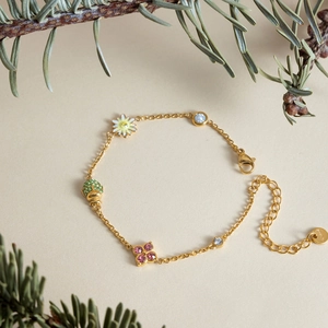 Detailed view of a gold-toned stainless steel bracelet with floral and ladybug charms
