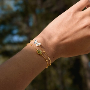 Detailed view of gold-tone stainless steel bracelets with butterfly and clover charms