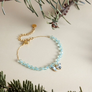 Macro view of butterfly pendant and light blue beads on stainless steel bracelet