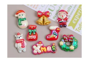 Flat lay of iridescent resin Christmas charms including Santa, snowman, and gingerbread man