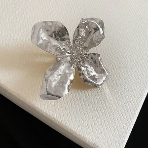 High-end detail view of an exaggerated silver hammered metal flower ring with texture