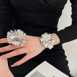 Detailed view of bold silver metallic flower ring and matching bracelet worn on wrist