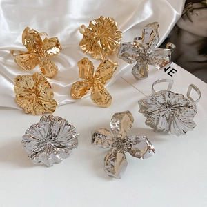 Detailed view of oversized gold and silver metallic flower bracelets and rings