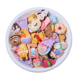 Colorful resin DIY charms with cartoon characters and flowers in a white bowl