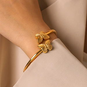 Elegante Nahaufnahme eines vergoldeten Schmetterlings-Armreifs aus Edelstahl am Handgelenk