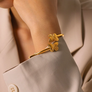 Nahaufnahme des vergoldeten Armreifs mit Schmetterlings-Detail auf 18 Karat Edelstahl