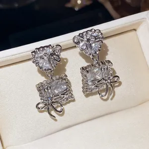 Elegant silver stud earrings featuring heart and square cubic zirconia with delicate bow motifs