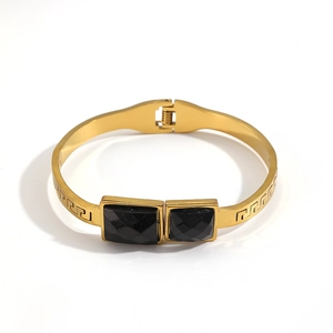 Elegant gold titanium steel bangle featuring faceted black square stones and Greek key pattern