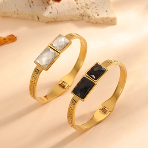 Detail of gold-plated bangles with black and white square stones and meander engraving
