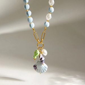 Close-up detail of shell and ceramic fish charms on blue beaded summer holiday necklace