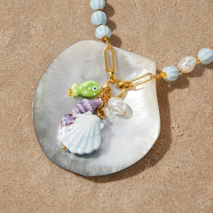Detailed macro view of ceramic fish and seashell charms on a beach style necklace