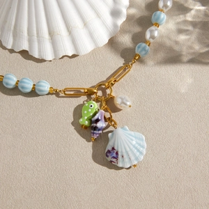 Close-up detail of beach vacation style necklace with ceramic shells and pearls