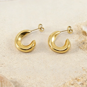 Polished 18K gold-plated stainless steel C-shaped hoop earrings on a sandy beach setting