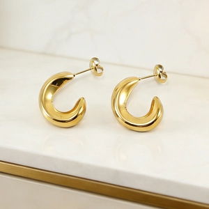 Detailed macro view of 18K gold plated stainless steel C-shaped hoop earrings on marble