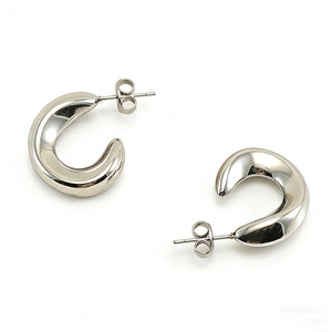 Close-up of polished silver C-shaped chunky hoop earrings with butterfly backings