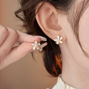 Close-up view of elegant gold-plated flower stud earrings with zircons on model ear
