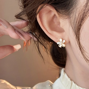 Close-up of a 18k gold plated flower stud earring with sparkling zircons and opal petals