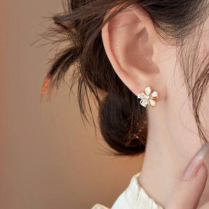 Close-up of elegant 18k gold plated flower stud earring with zircons on ear