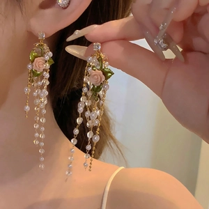 Dettaglio macro di orecchini vintage francesi con rose, perle e perline di cristallo