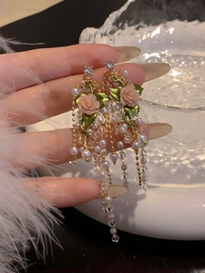 Dettaglio degli orecchini a rosa vintage con eleganti nappe di perle e cristalli lucidi