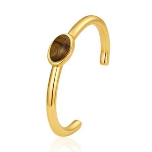 Professionele close-up van een gouden C-vormige armband met een ovale tijgeroog edelsteen