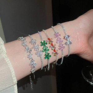 Primer plano de exquisitas pulseras de flores y lazos de circonita chapadas en oro de 18k