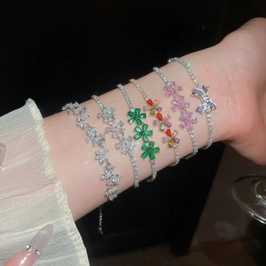 Primer plano de varias pulseras de flores y lazos de circonita bañadas en oro de 18 quilates